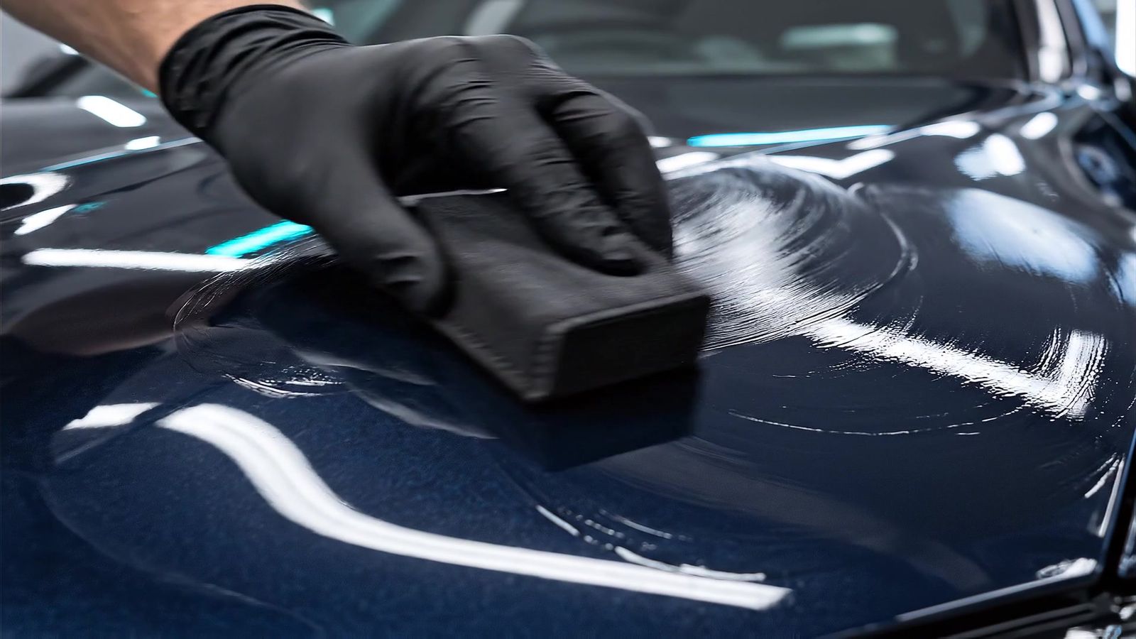 Zwarte applicator met glascoating op een glanzende motorkap