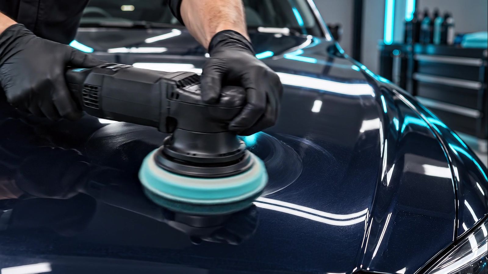 Polijstmachine op de motorkap van een donkerblauwe auto in een detailingstudio